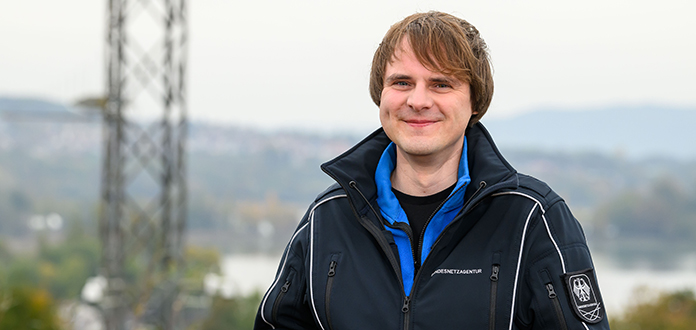 Junger Mann mit blauer Jacke vor unscharfem Hintergrund 